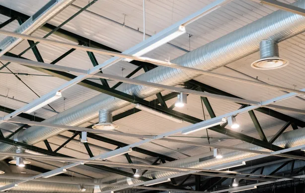 Industrial facility with high-bay LED lighting illuminating heavy equipment and steel structural framework