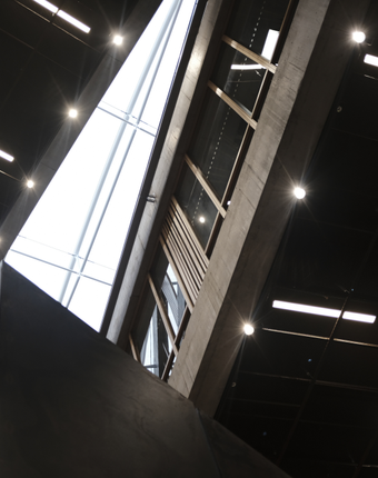 Large warehouse interior with rows of LED panel lights illuminating stacked pallets and distribution aisles