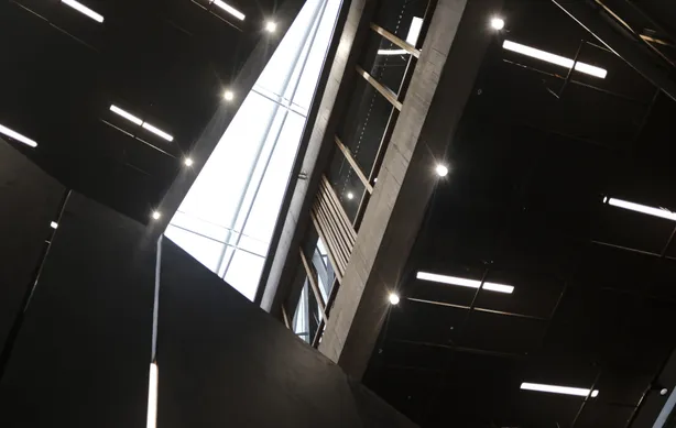 Large warehouse interior with rows of LED panel lights illuminating stacked pallets and distribution aisles